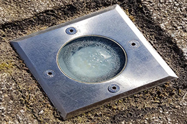 Image thématique : projecteur encastré au sol avec des gouttes d’eau sur le verre